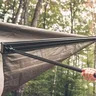 Person setting up a tent in a wooded area.