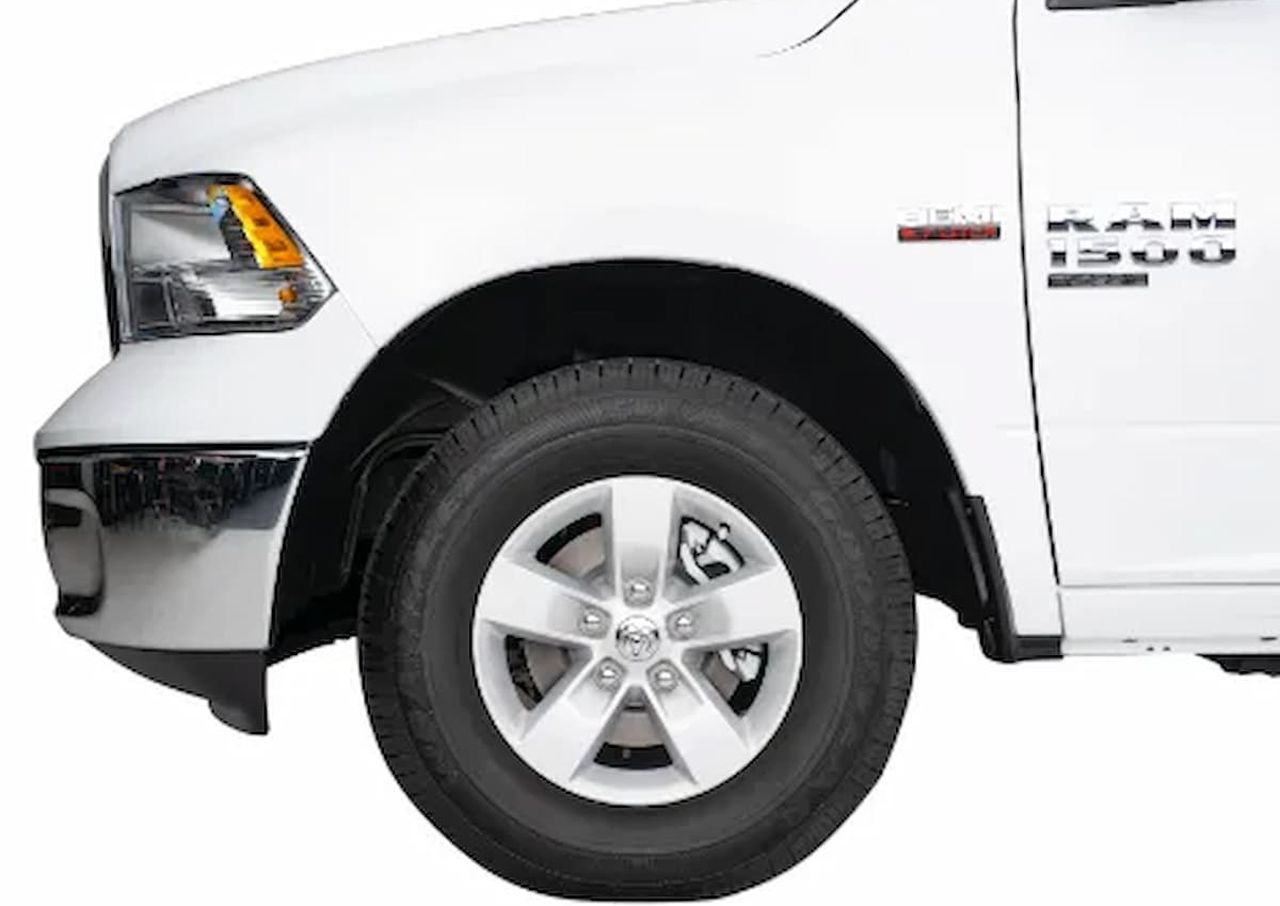 Front side of a white RAM 1500 pickup truck with a visible wheel and badge.